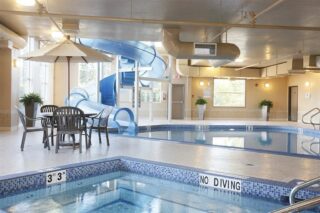A brightly lit room featuring a pool & hot tub with waterslide.