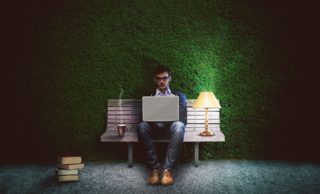 Man typing on bench.